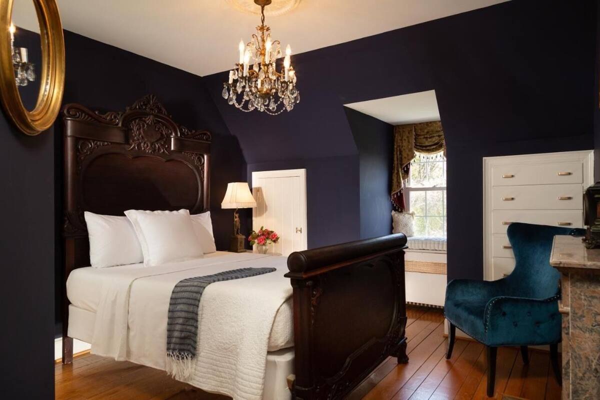 Une chambre à coucher avec un grand lit, un lustre, une commode et une chaise.