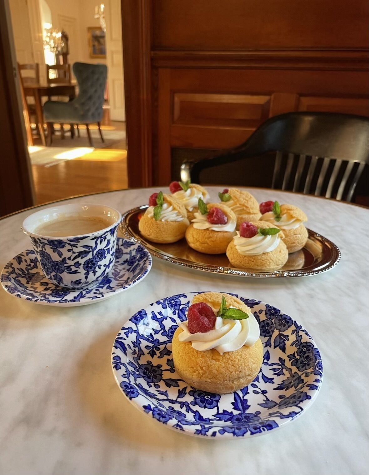 Une table avec une assiette à motifs floraux, une tasse et un plateau de pâtisseries.