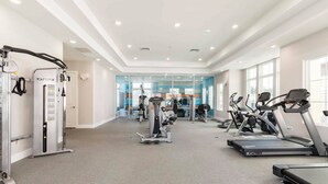 A gym with treadmills, weight machines, and a mirrored wall. - 4 Suites Villa 5 min to Disney (Kissimmee)