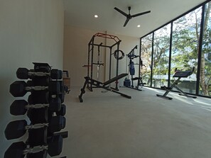 Un gimnasio con equipo de ejercicio diverso, incluyendo mancuernas, una prensa de banca y una estructura para sentadillas.
