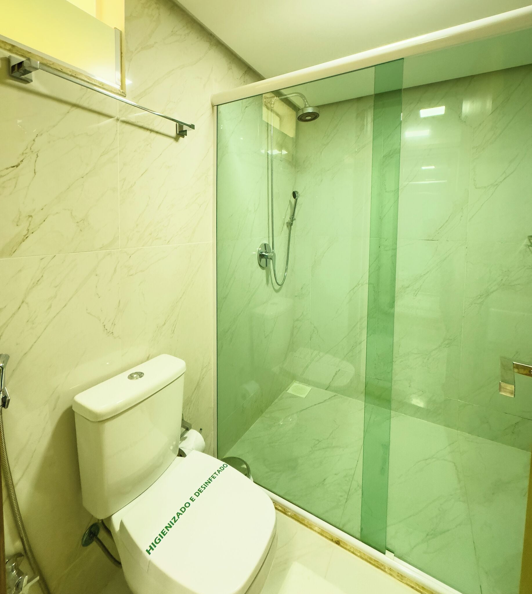 Une salle de bain avec des toilettes, une douche en verre et des murs en marbre.