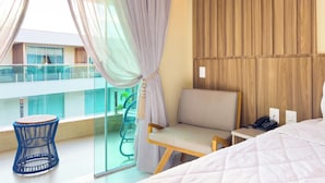 Una habitación de hotel moderna con balcón, un panel de pared de madera, una cama, una silla y una mesita.