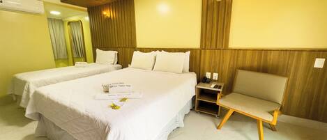 A hotel room with two beds, a desk, and a chair.
