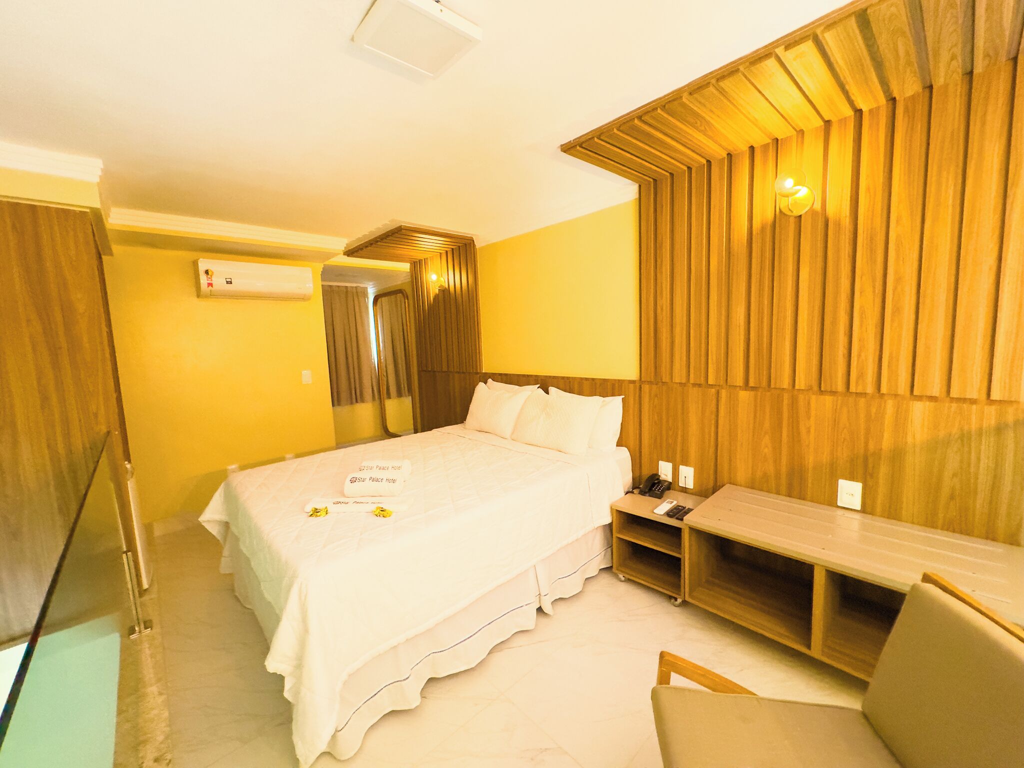Una habitación de hotel con cama, mesita de noche y un pequeño escritorio.