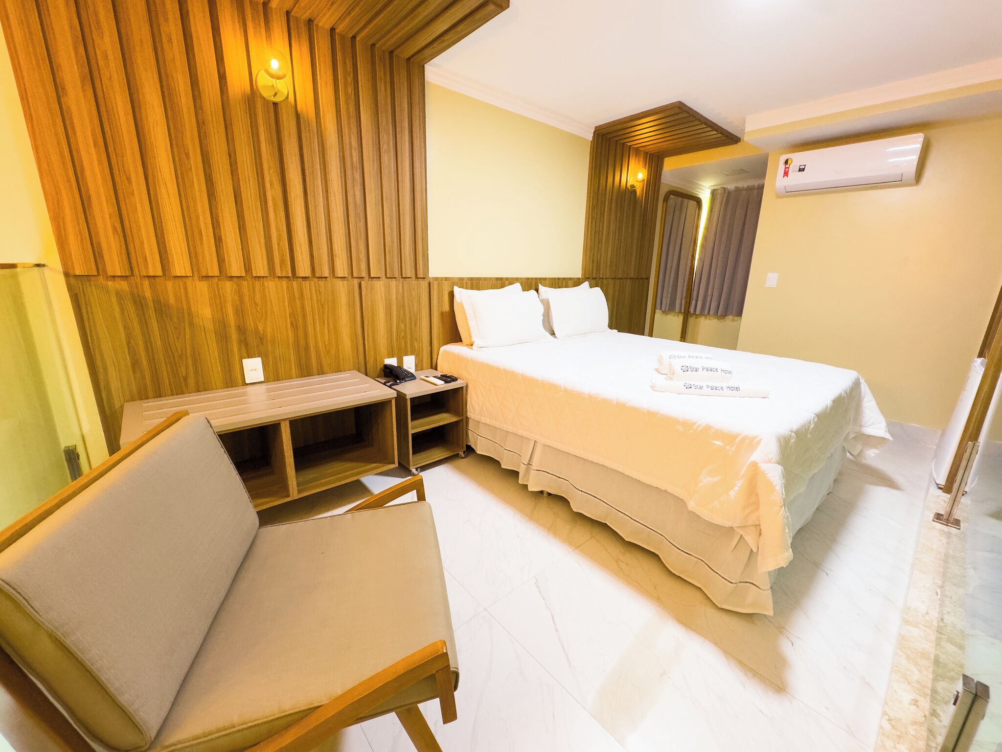 Une chambre d’hôtel équipée d’un lit, d’un bureau, d’une chaise, d’une table de chevet et d’un appareil de climatisation.