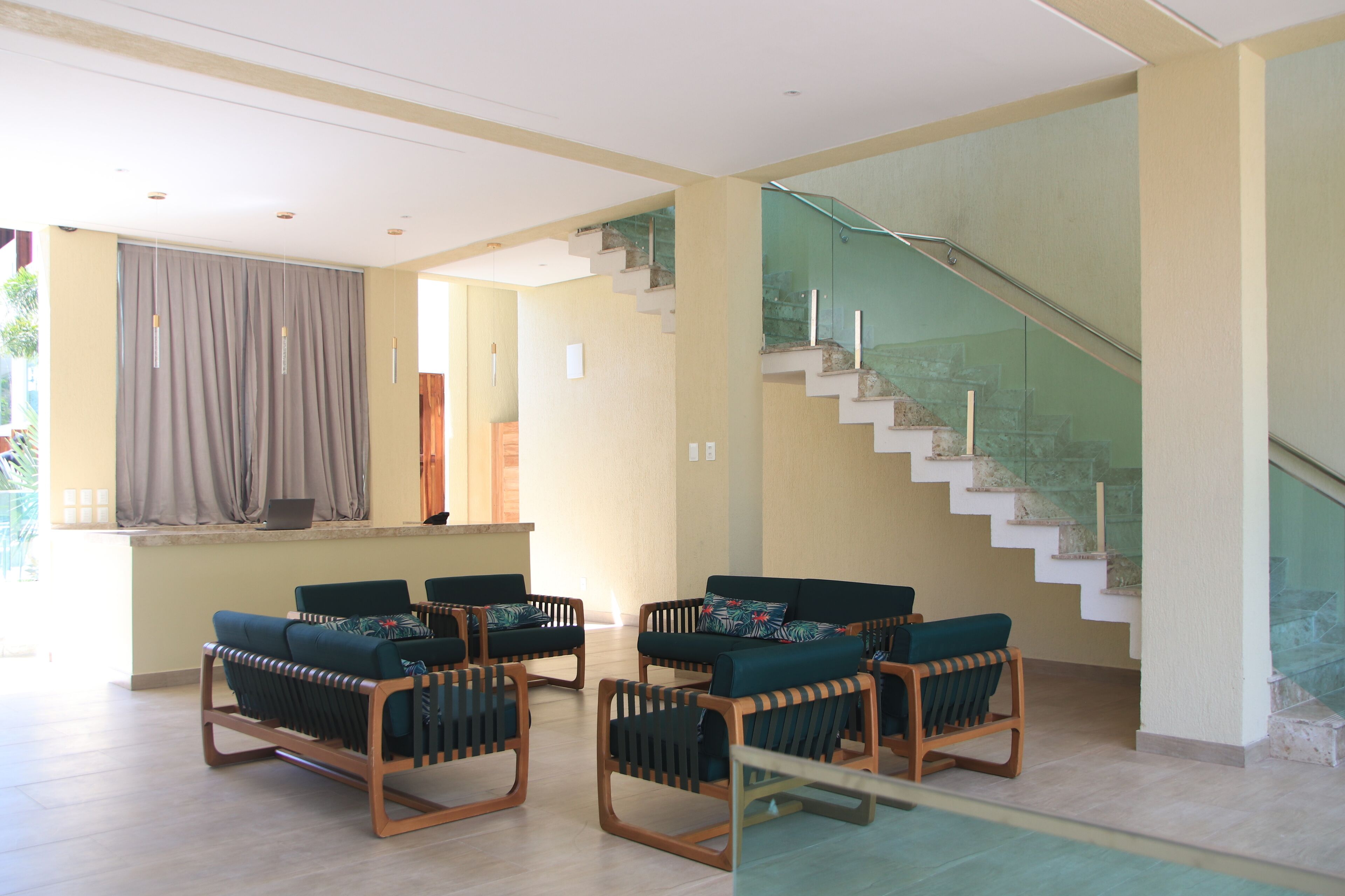 Amplia sala de estar con una escalera moderna, un conjunto de asientos con sillones cómodos y una cocina a la vista.