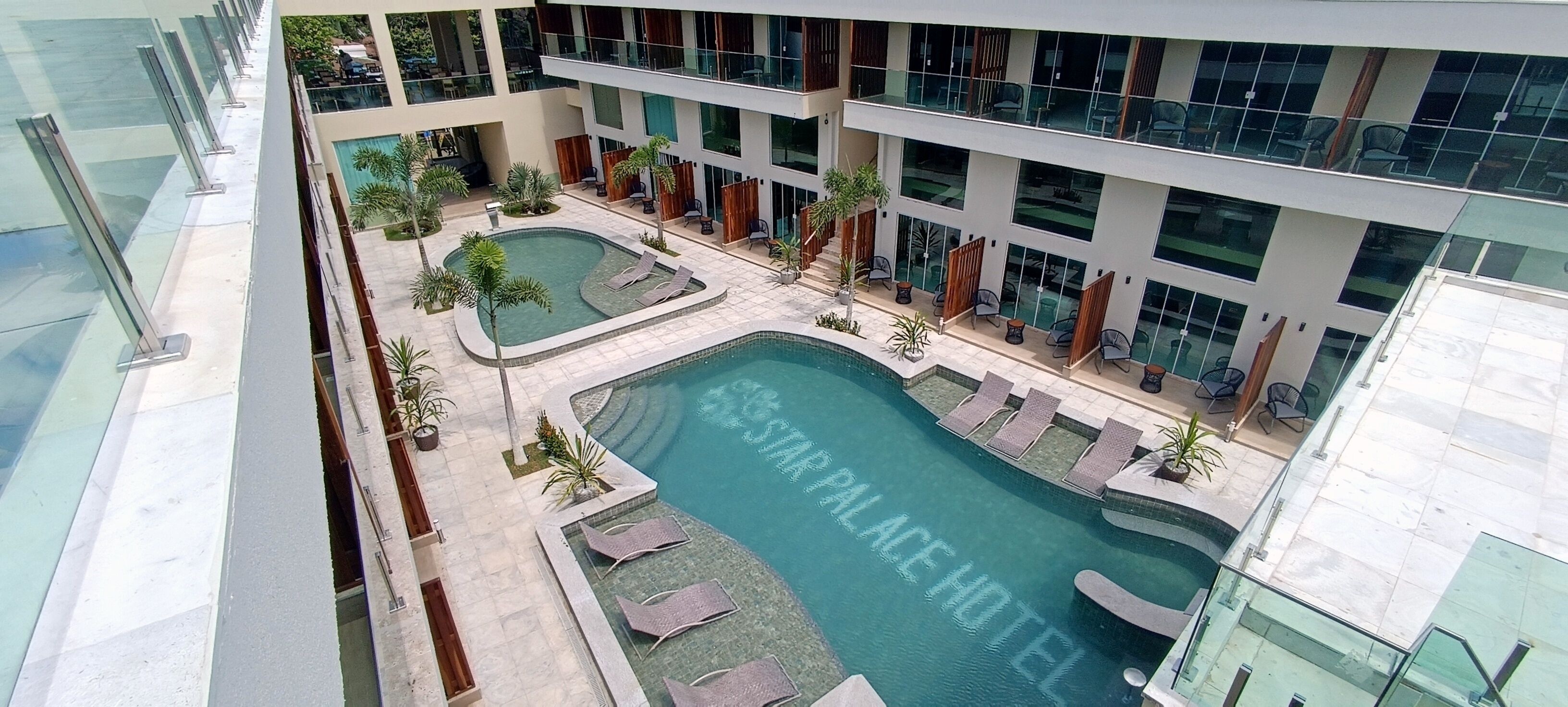 Ein Poolbereich auf dem Dach mit Liegestühlen und einem Schild mit der Aufschrift 'Sapphire Place Hotel'.