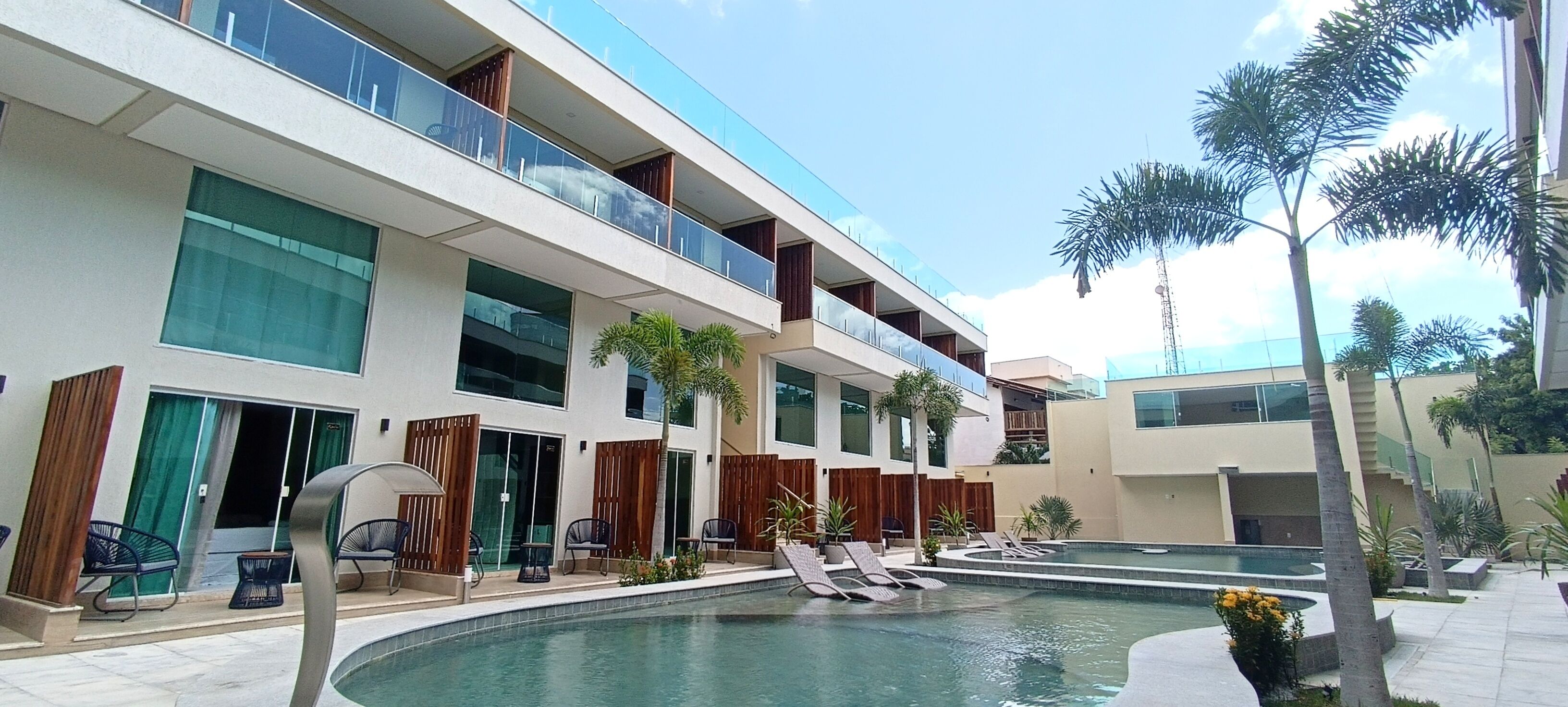 Ein modernes Hotel mit Poolbereich, mehreren Balkonen und Außenbereich zum Sitzen.