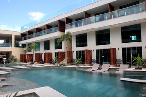 Un hotel moderno con zona de piscina, varios balcones y una combinación de asientos interiores y exteriores.