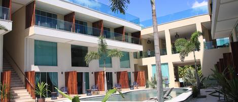A modern hotel with a pool area, multiple balconies, and a staircase leading to the upper floors.