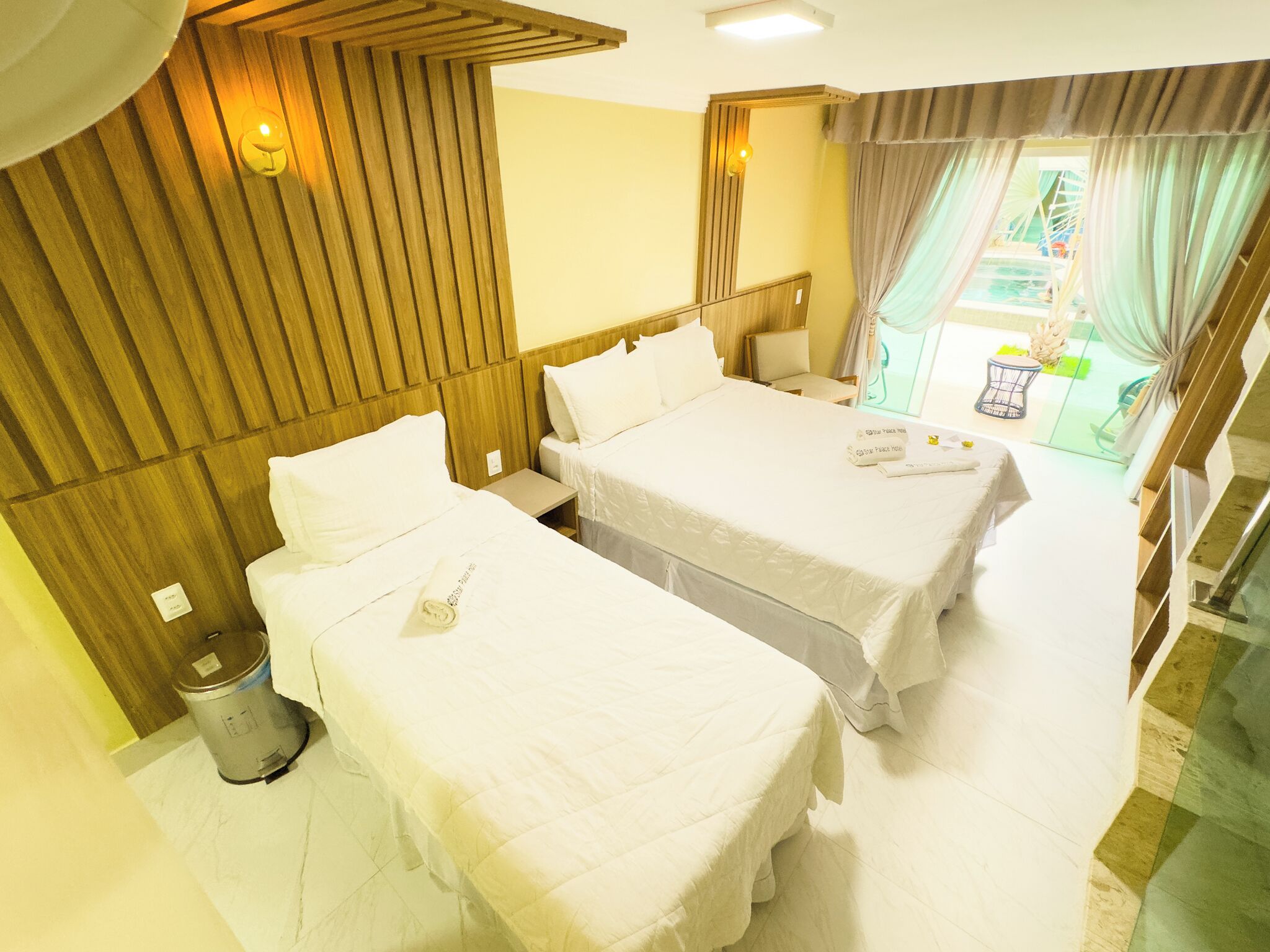 Ein Hotelzimmer mit zwei Betten, einem kleinen Tisch und einem Mülleimer.