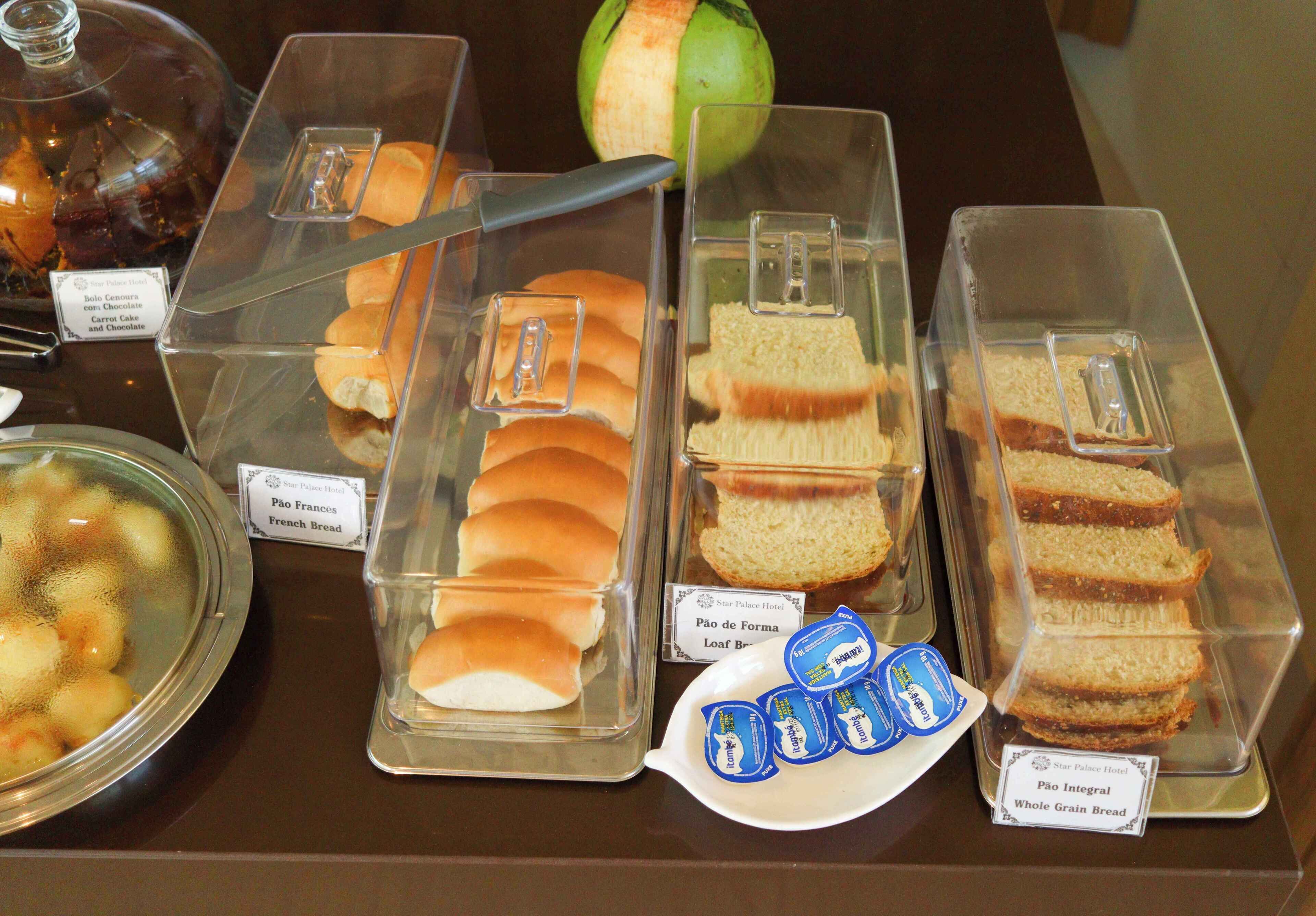 Un bufé con diversas opciones de comida, incluyendo pan, pastelería y una cesta de fruta.