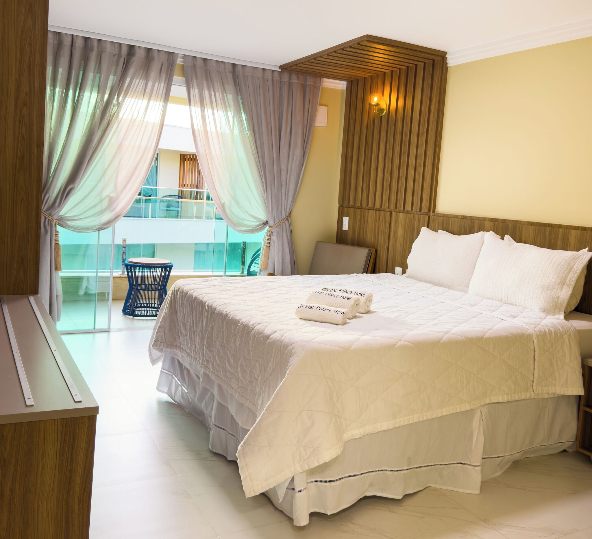 Habitación de hotel con una cama grande, un escritorio y vistas a un balcón.