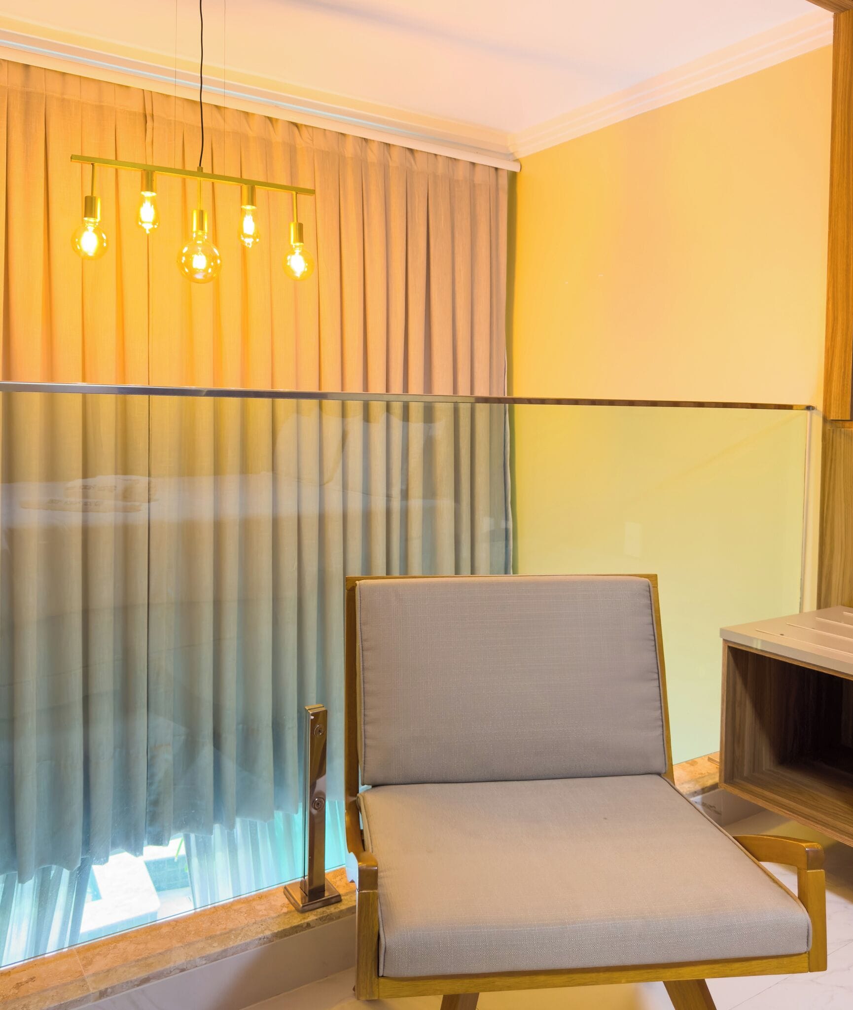 Une pièce comprenant une chaise, une cloison en verre et un luminaire.