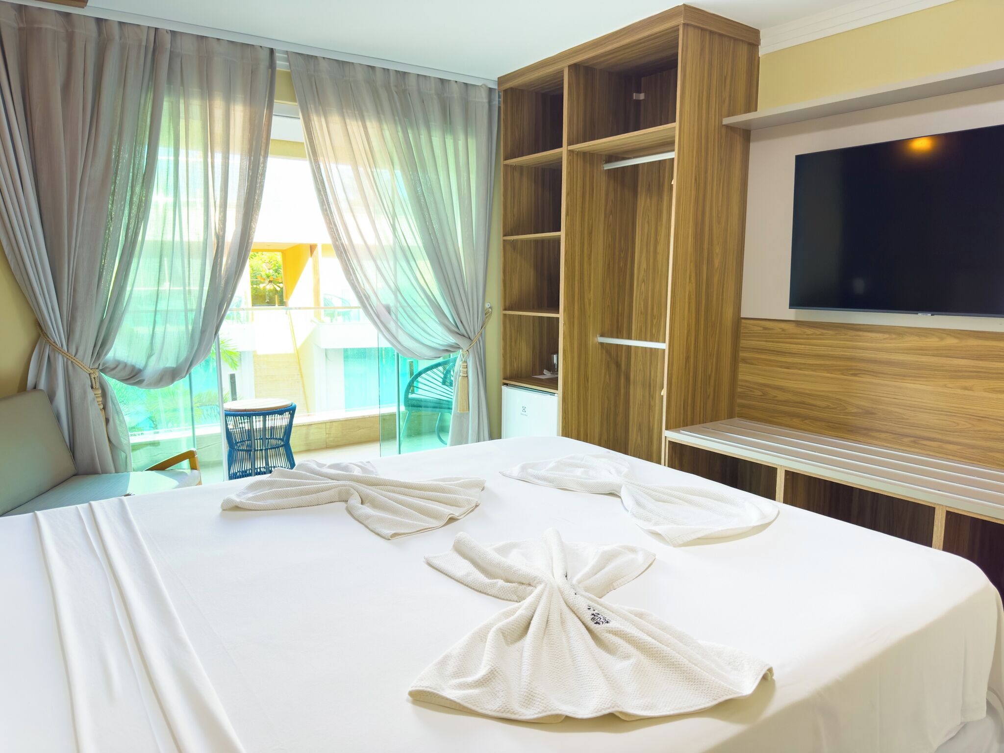 A hotel room with a bed, a TV, and a wooden wardrobe.