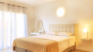 A hotel room with a large bed, a bedside table with a lamp, a mirror, and a window with sheer curtains. - B&B Albufeira City Room Junior with Private Bathroom (Albufeira)