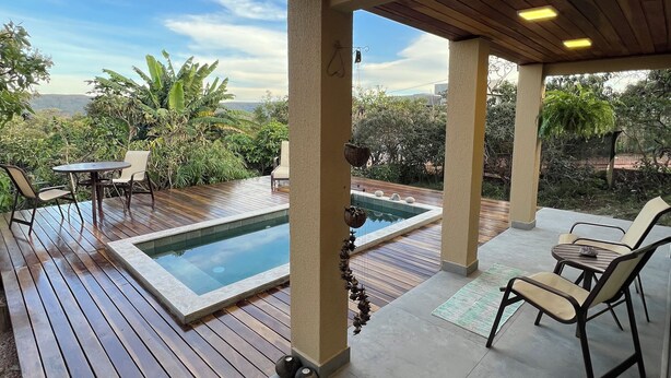Un espace extérieur abrité comprenant une piscine, une terrasse en bois et des sièges.