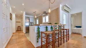 A modern kitchen with a central island, wooden bar stools, and pendant lighting. - Apartment Nautica Bay Moraira (Moraira)