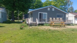 A two-story house with a covered porch, a small deck, and a picnic table.