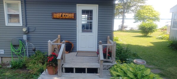 A house with a wooden deck, a welcome sign, a doghouse, and a pond. - 3 bedroom house on Manistique Lake (McMillan)