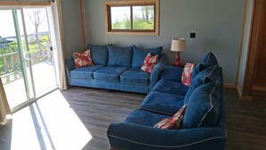 Ein Zimmer mit einem blauen Sofagarnitur, einem Fenster mit Holzrahmen und einer Lampe auf einem Beistelltisch.
