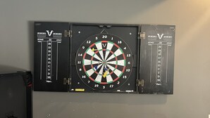 Un tablero de dardos colgado en una pared con un marcador a un lado.