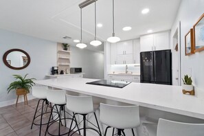 A modern kitchen with a central island, white cabinetry, and a black refrigerator. - Mango Tree by the Sea, Hutchinson Island - Bungalow B! (Fort Pierce)
