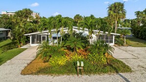 Una casa moderna amb un jardí gran, envoltada de palmeres i altra vegetació.