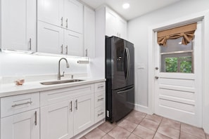 Enjoy cooking in this well-equipped kitchen with a stainless steel sink and a refrigerator, plus a window with a view.