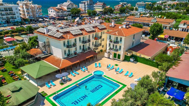 A hotel with a swimming pool, multiple balconies, and a view of the sea. - Sunlight Otel Fethiye (Fethiye)
