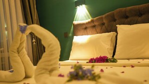 A neatly made bed with a swan-shaped towel, a green wall, and a tufted headboard. - Sunlight Otel Fethiye (Fethiye)