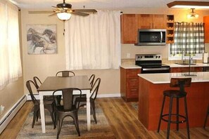 A kitchen with a dining table, chairs, a microwave, and a stove.