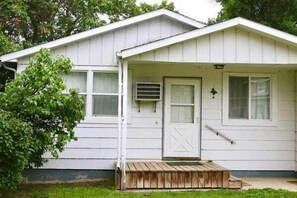A single-story house with a front porch, a door, and a small window.