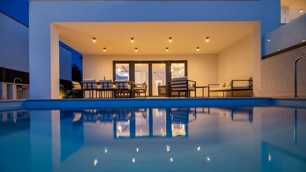 A modern house with a swimming pool, outdoor seating, and a well-lit patio area. - Villa Aria with heated pool & Seaview (Klimno (Krk))