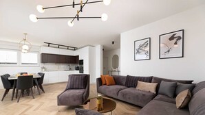 A modern living room with a sectional sofa, a dining area with a table and chairs, and a kitchen in the background. - Villa Aria with heated pool & Seaview (Klimno (Krk))