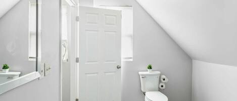 Een moderne badkamer met een wit toilet, een wastafel en een spiegel.