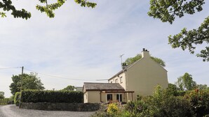 A single-story house with a stone wall and a gravel driveway.