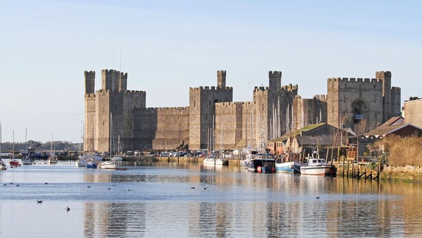 A historic castle with a moat and boats docked in the foreground.