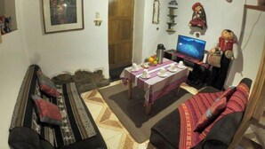 Ein gemütliches Wohnzimmer mit einer Sofagarnitur, einem Fernseher und einem Tisch mit Tassen.