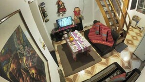 Ein Wohnzimmer mit einer Couch, einem Fernseher, einem Tisch mit Gegenständen und einer Treppe.