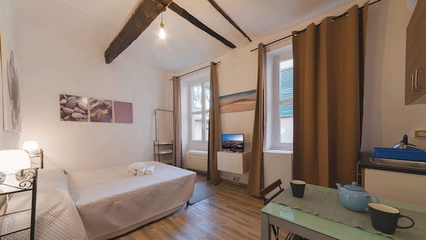 Une chambre compacte comprenant un lit, une table de chevet et un petit coin cuisine.