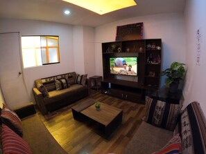A living room with a sofa, a coffee table, a TV, and a bookshelf.