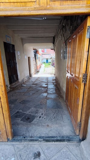 Un pasillo con piso de piedra que conduce a una puerta de madera.