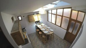 A compact kitchen with a dining area, a small kitchenette, and a window providing natural light. - Ekeko's Apartment - Calle Matara (Cusco)
