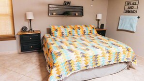 A bedroom with a bed, two nightstands, a wall-mounted shelf, and a towel rack.