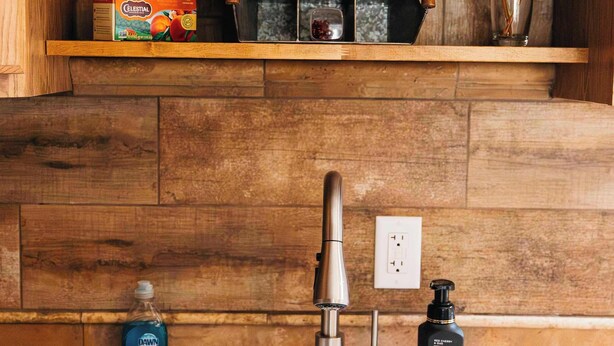A kitchen with wooden cabinets, a white sink, a soap dispenser, and a spice rack.