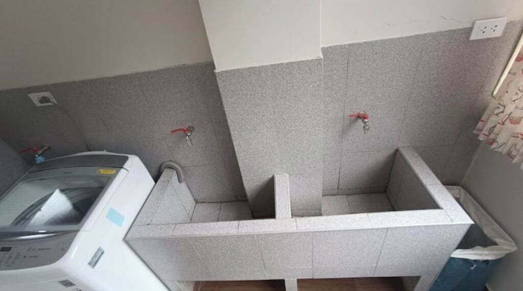 A small laundry room with a washing machine, two towel racks, and a tiled floor.