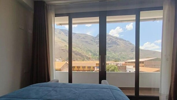A room with a bed, a view of mountains, and a balcony with a door. - Casita de Diego (Calca)