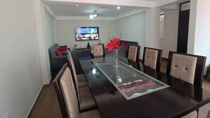 A dining area with a glass-top table, six chairs, and a red flower centerpiece. - Casita de Diego (Calca)