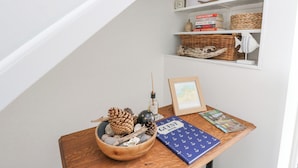 A wooden table with a bowl of pinecones, a framed map, and a blue book titled "GUEST BOOK". - Anchor Cottage (Elgin)